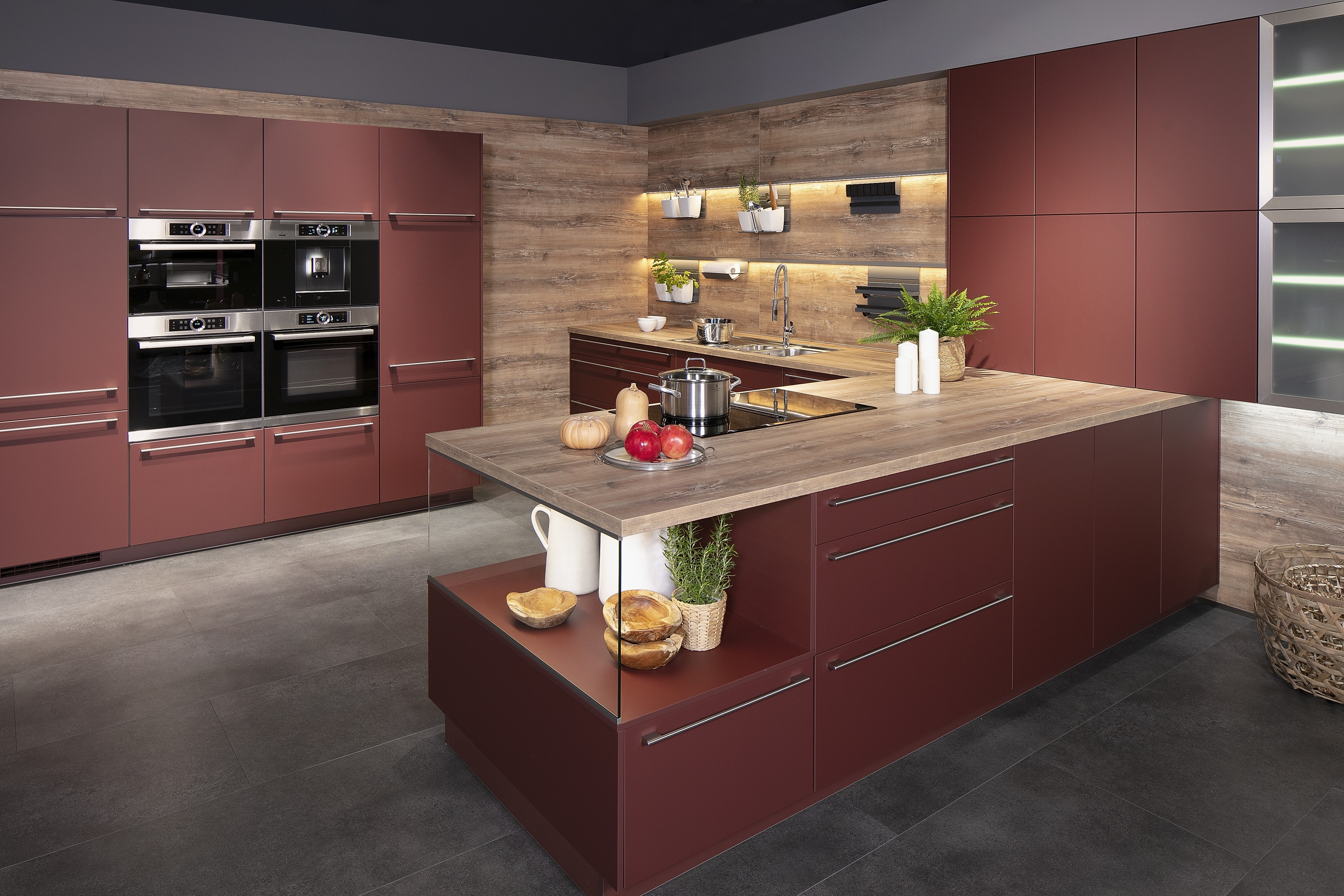 Küche von Nobilia in Rostrot mit Arbeitsplatte im Pinie-Dekor und mit Glas-Vitrine