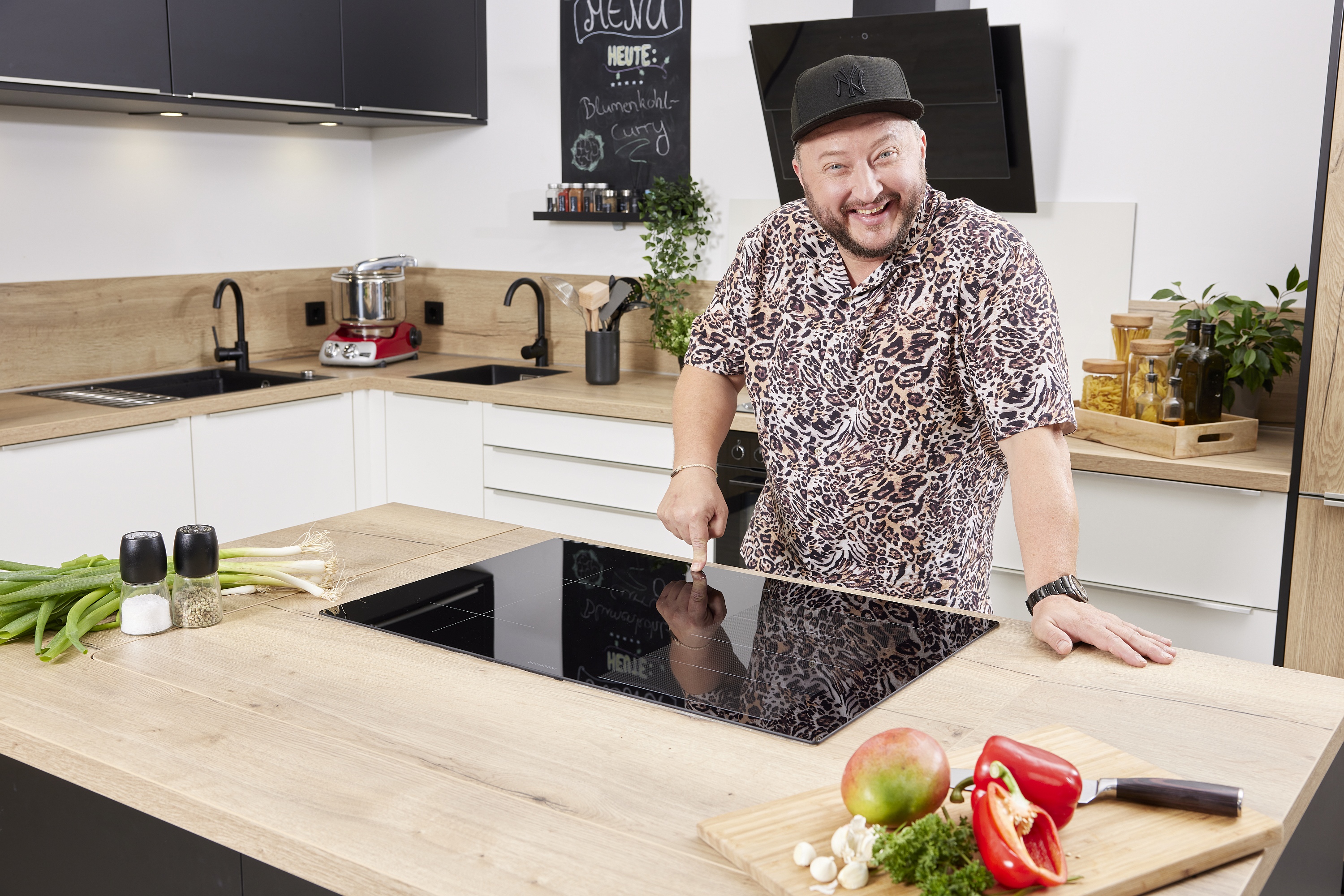 ORANIER Induktionskochfeld in Kochinsel lachender Mann zeigt die Bedienung
