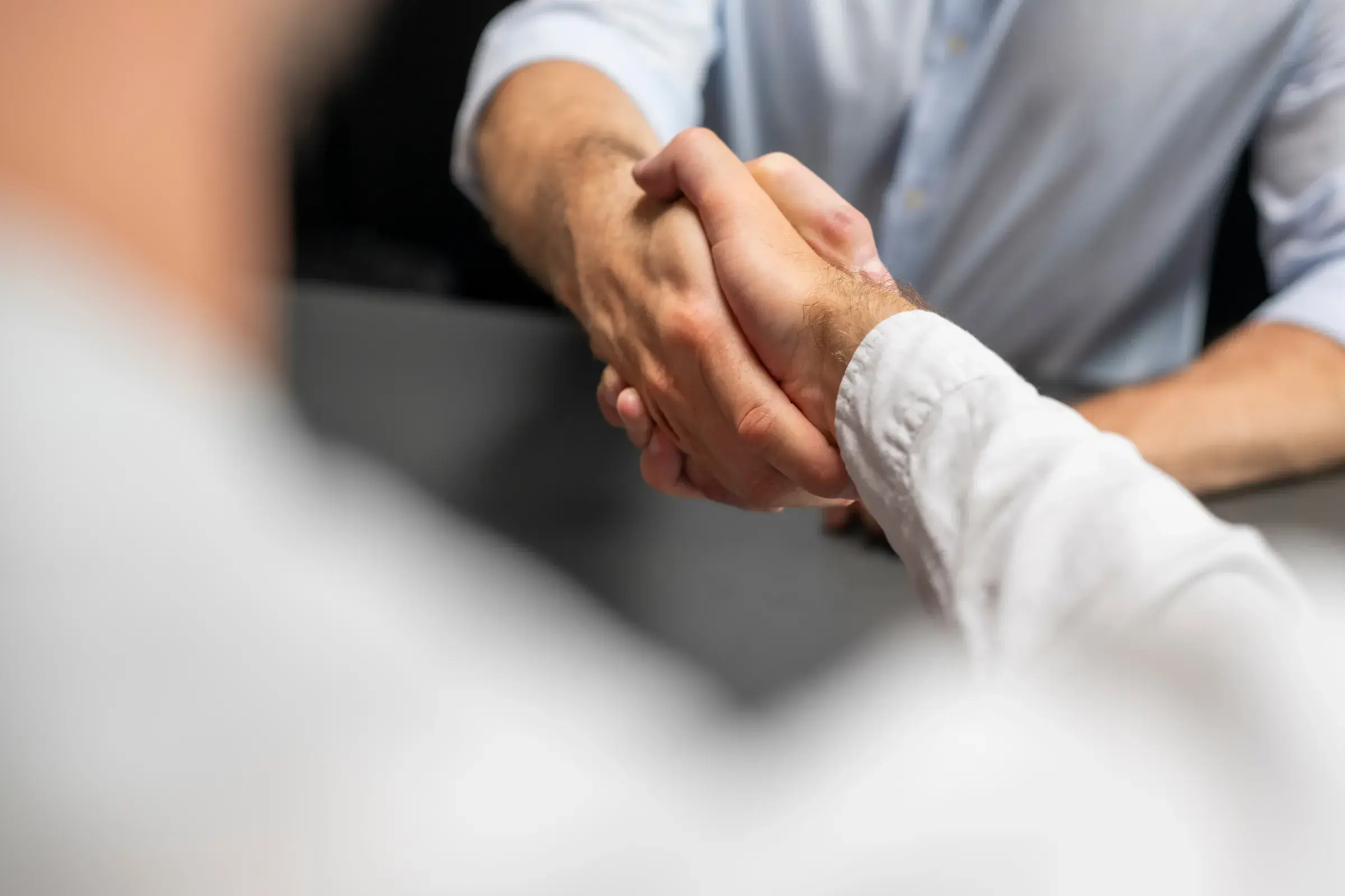 Über-die-Schulter-Perspektive auf Handschlag zwischen zwei Männern